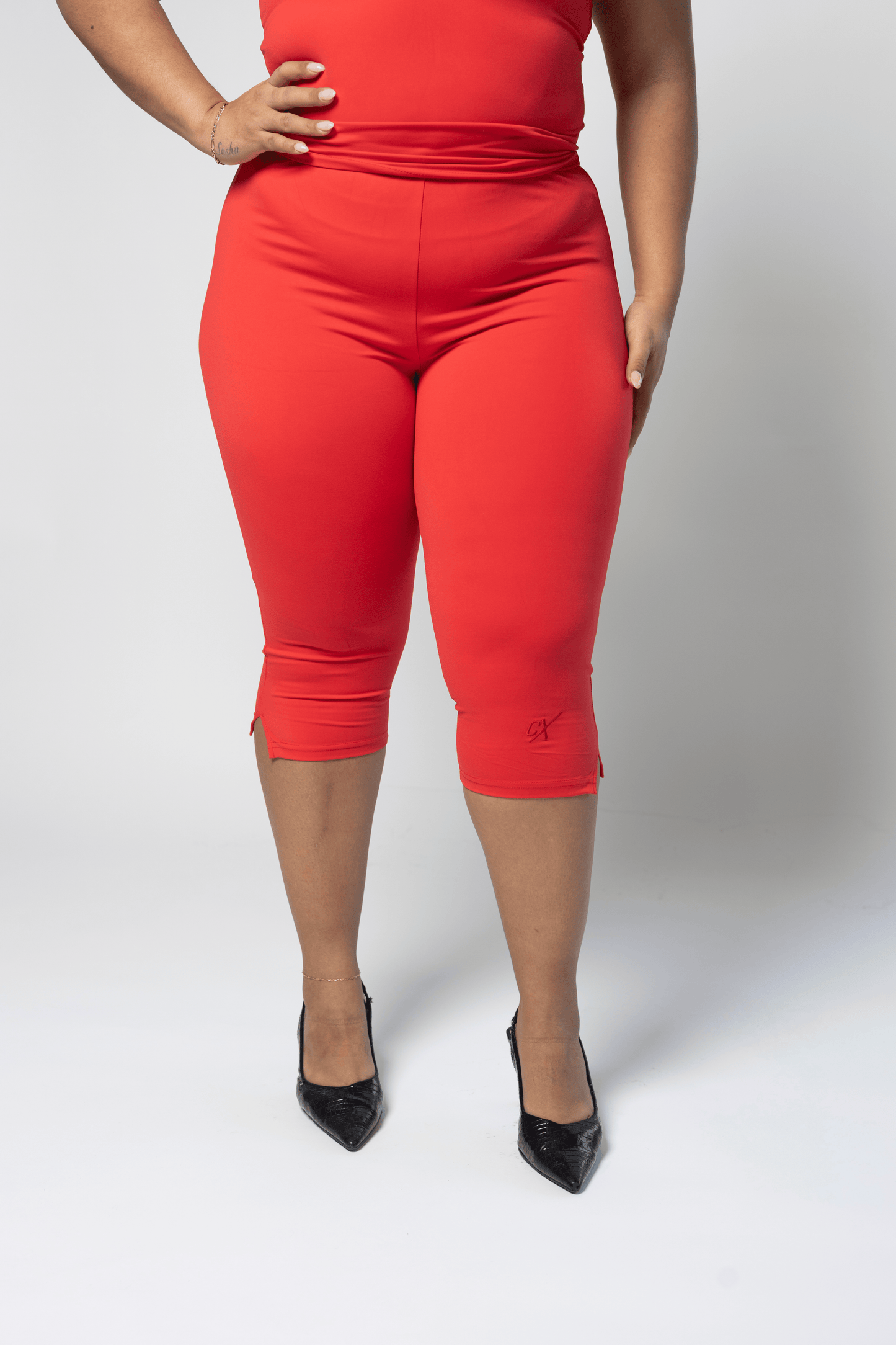 Person wearing red capri pants on a white background